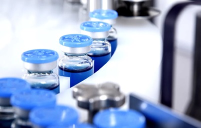 Photograph of vials of liquid moving through a machine conveyor belt