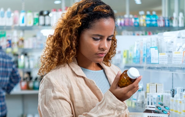 Woman looking at bottle of medicine in pharmacy