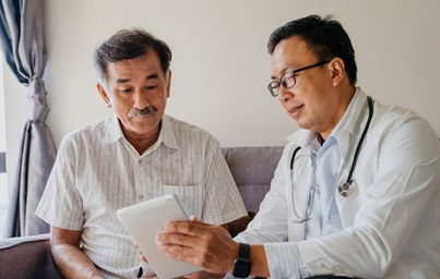 A doctor showing a middle-aged male patient information on a tablet