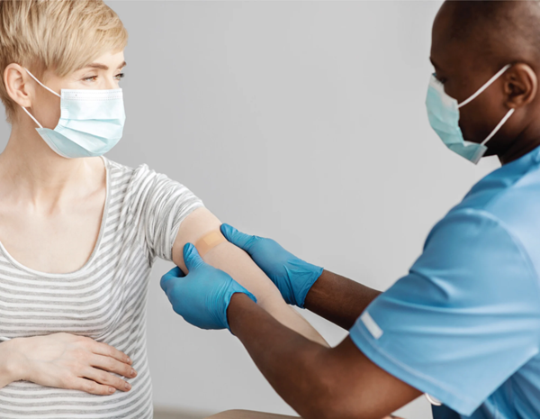 Nurse applying a bandage to patient after administering a vaccine shot